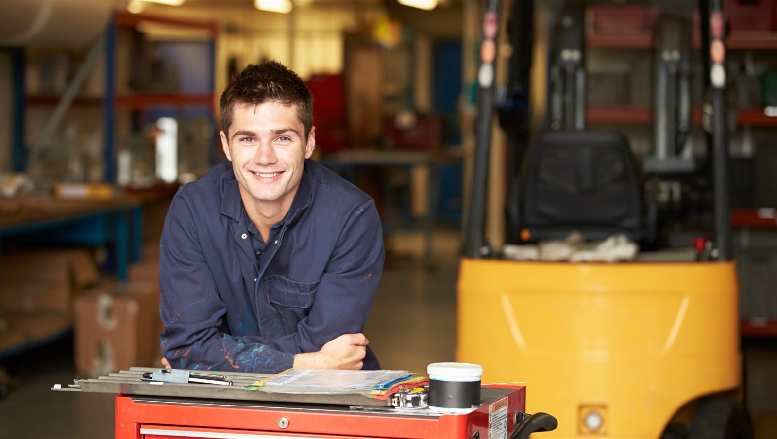 Apprentice leaning on a tool cart in a workshop