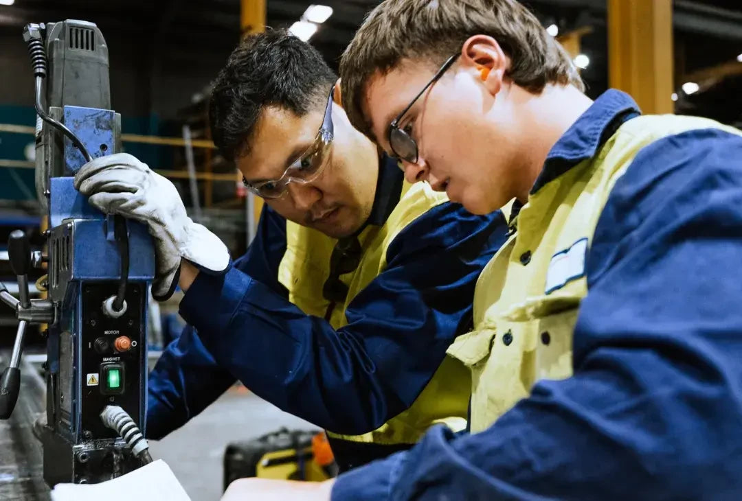 Tradesperson guiding an apprentice on a magnetic drill